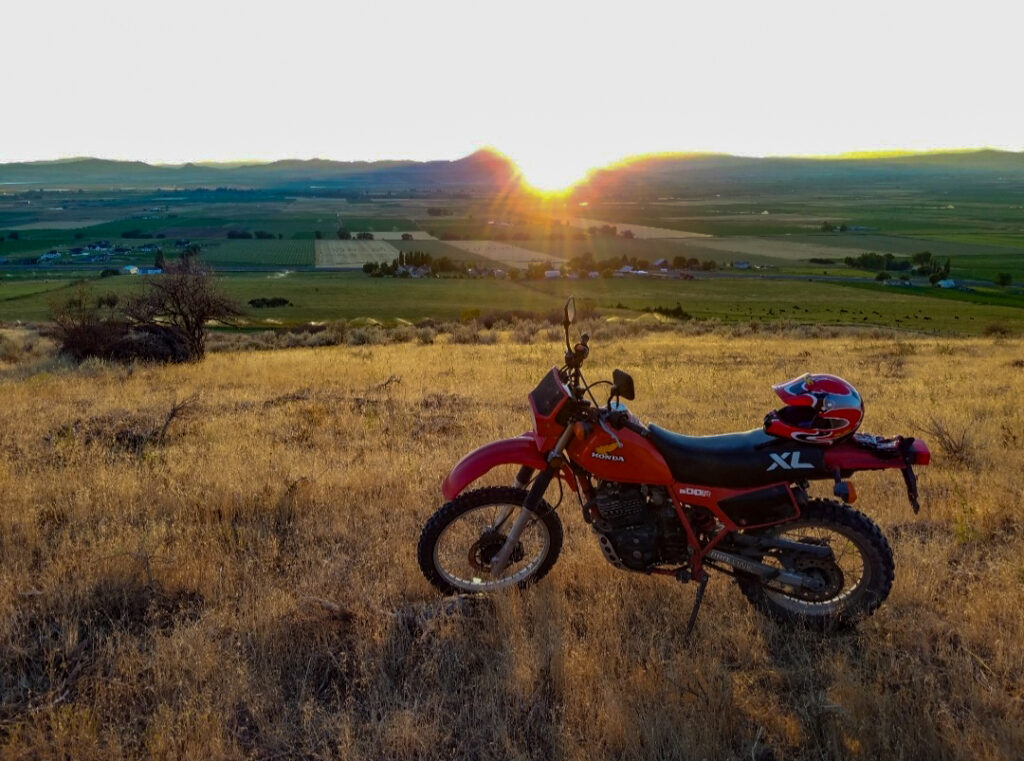 Honda XL600R motorcycle in front of a sunset landscape.